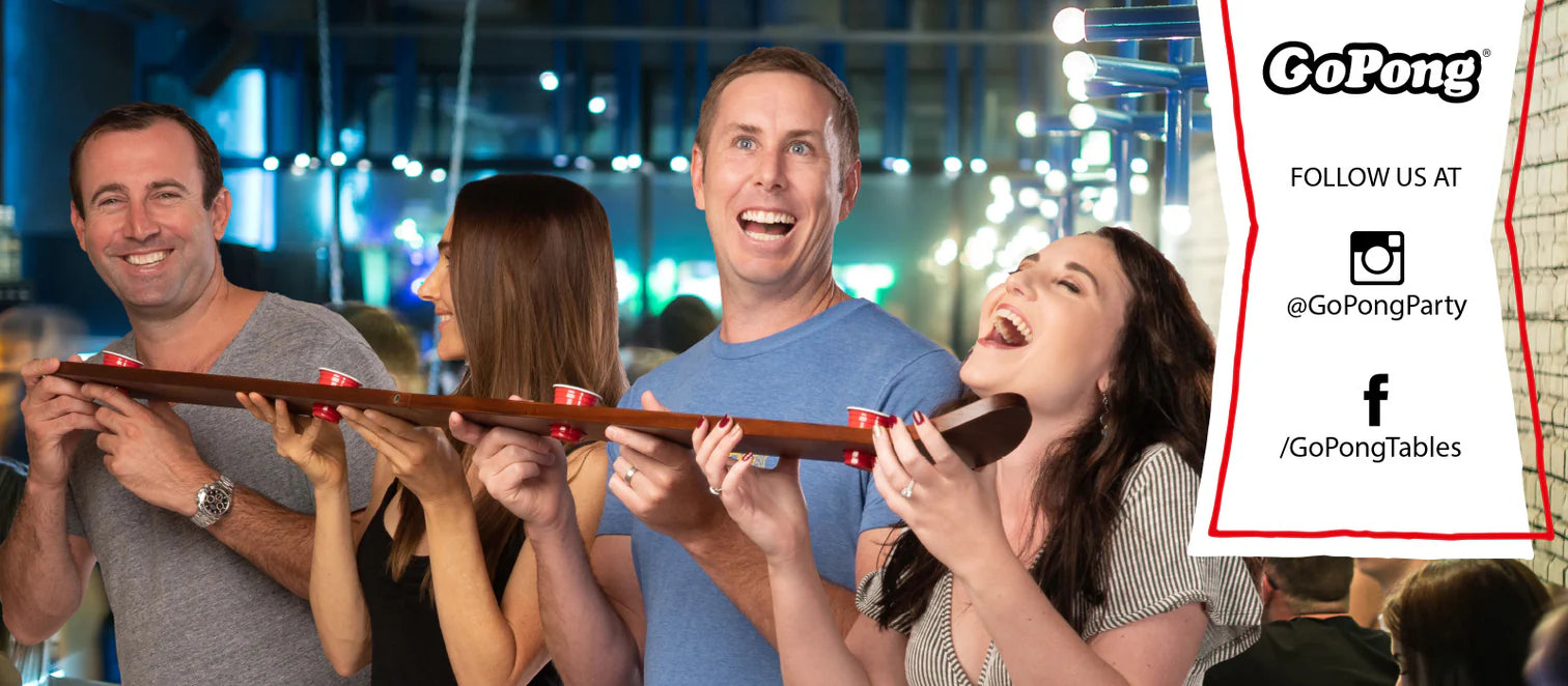 A group of people joyfully engaging with a long stick, showcasing camaraderie and fun in an outdoor setting.
