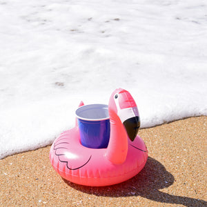 a pink flamingo toy sitting on the beach